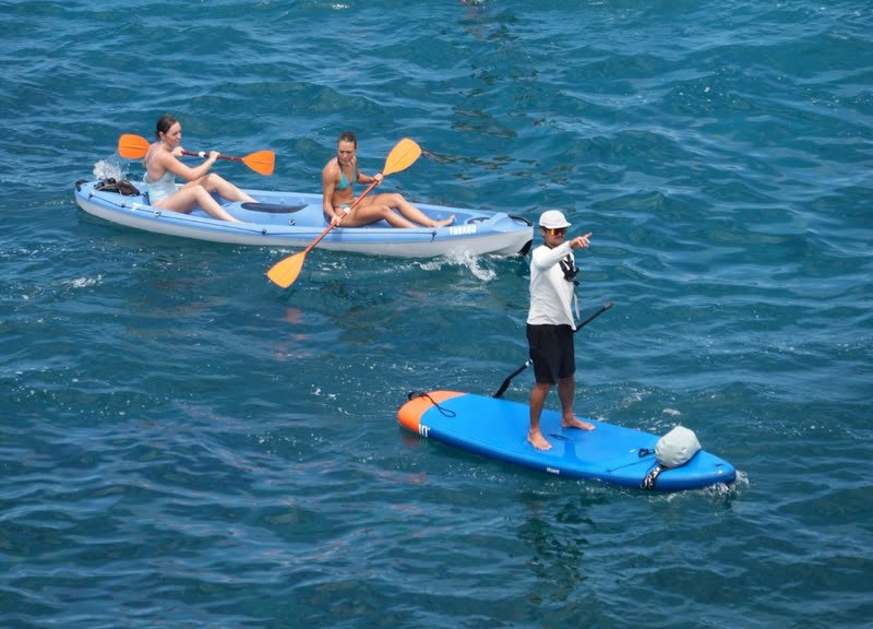El monitor en su tabla acompaña a dos chicas en kayak