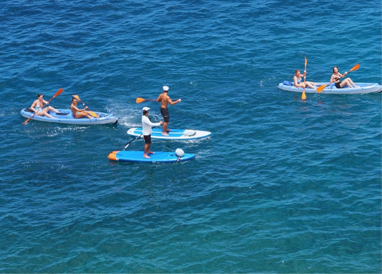 Kayaks y una tabla de paddle surf en mar abierto