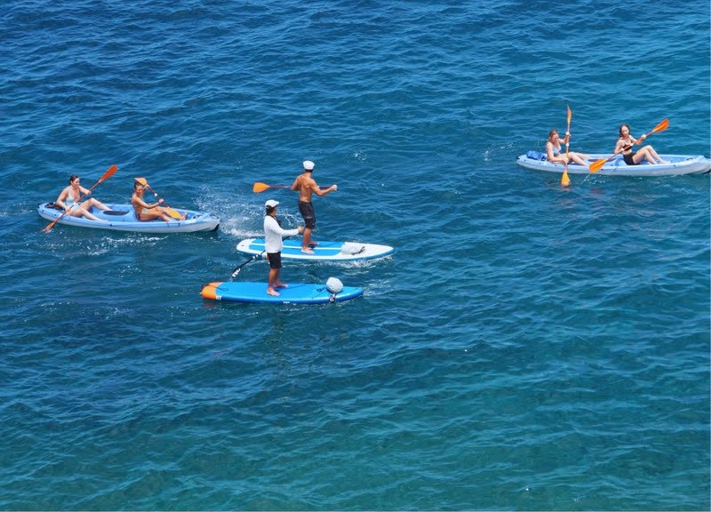 Kayaks y una tabla de paddle surf en mar abierto